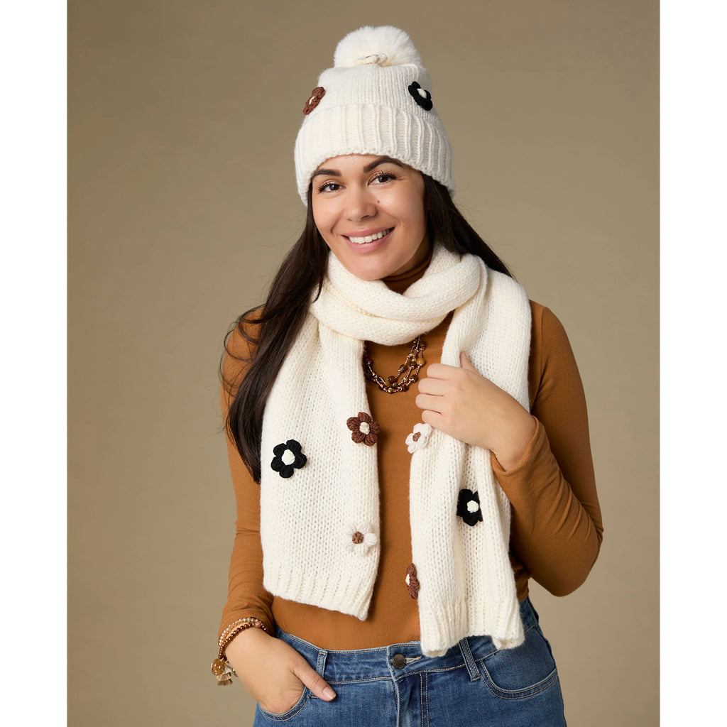 Soft knit hat with flower embellishments and fluffy pom, cozy winter accessory.