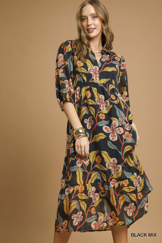 Woman wearing black midi dress with bold mixed floral print and tiered hem