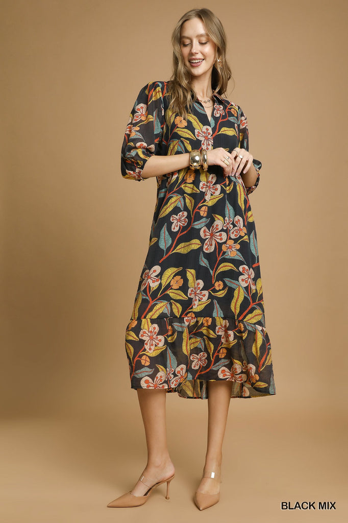Woman wearing black midi dress with bold mixed floral print and tiered hem