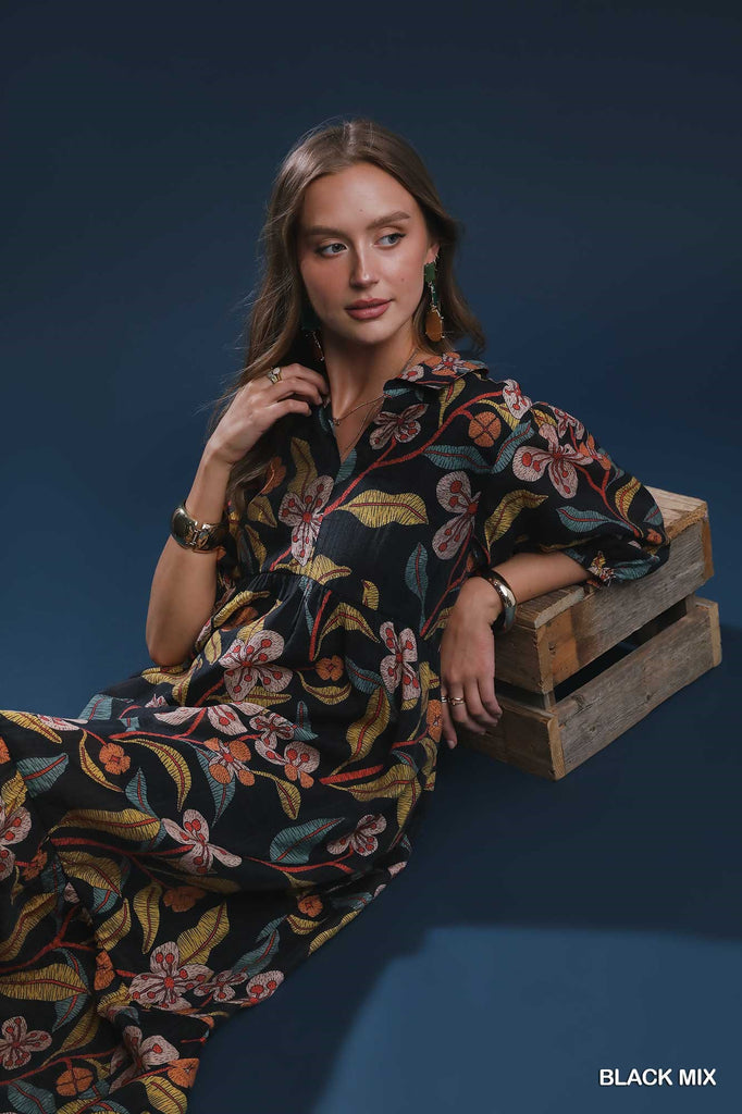 Woman wearing black midi dress with bold mixed floral print and tiered hem