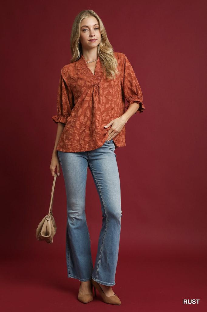 Woman wearing rust Floral Jacquard V-Neck Top with ruched neckline and ¾ sleeves