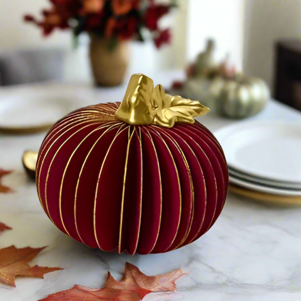 Decorative red pumpkin with a gold stem on a white background