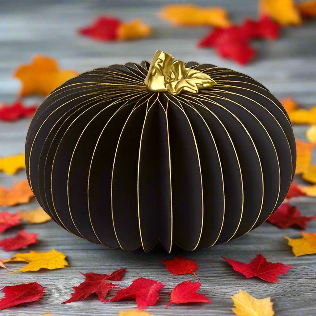 Black decorative pumpkin with gold accents on a white background