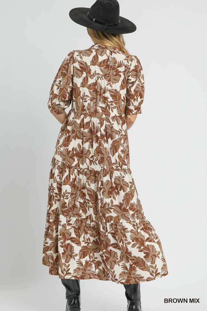 Woman wearing a brown and white floral dress with a black hat on a light gray background