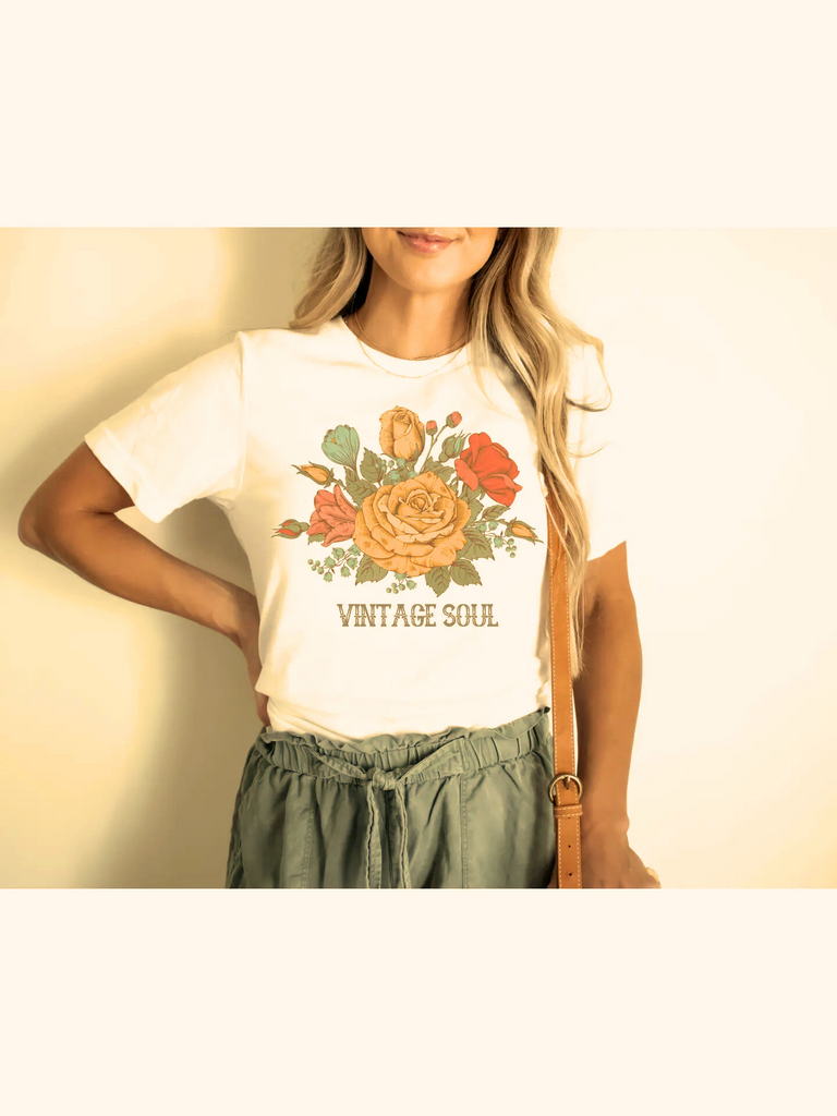 Person wearing a white t-shirt with floral design and 'Vintage Soul' text on a plain background