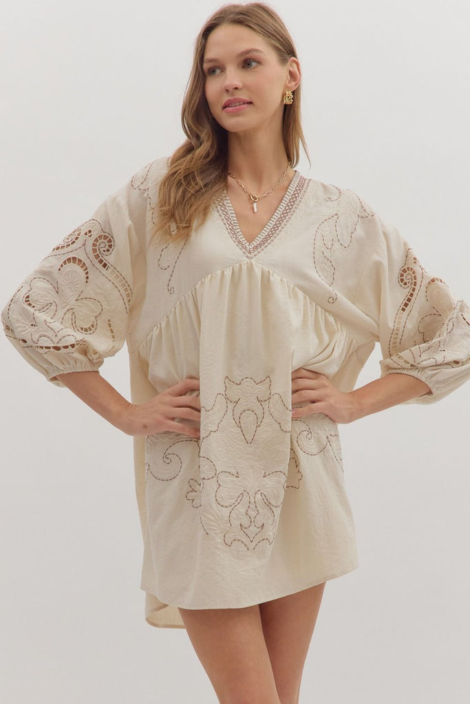 Floral embroidered mini dress with 3/4 sleeves, V-neckline, and eyelet sleeve cutouts in cream.