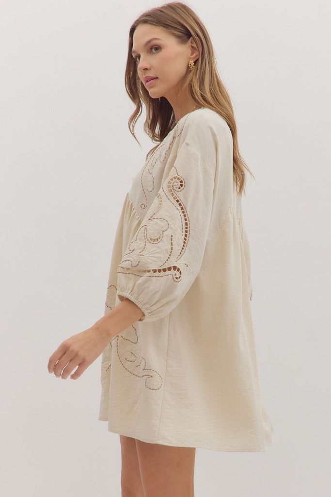 Floral embroidered mini dress with 3/4 sleeves, V-neckline, and eyelet sleeve cutouts in cream.